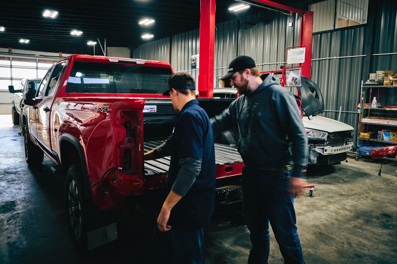 Dent Magic technicians working at the tailgate of a truck in the shop